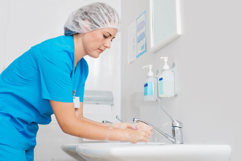 nurse washing hands at hospital sink